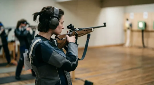 Tireur olympique en pleine concentration visant une cible ISSF avec équipement professionnel